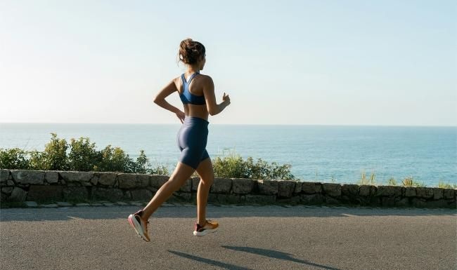 a woman running on a road by the water